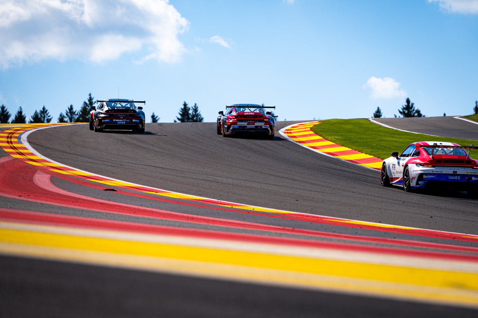 3 Porsche racecars flying over Eu Rouge