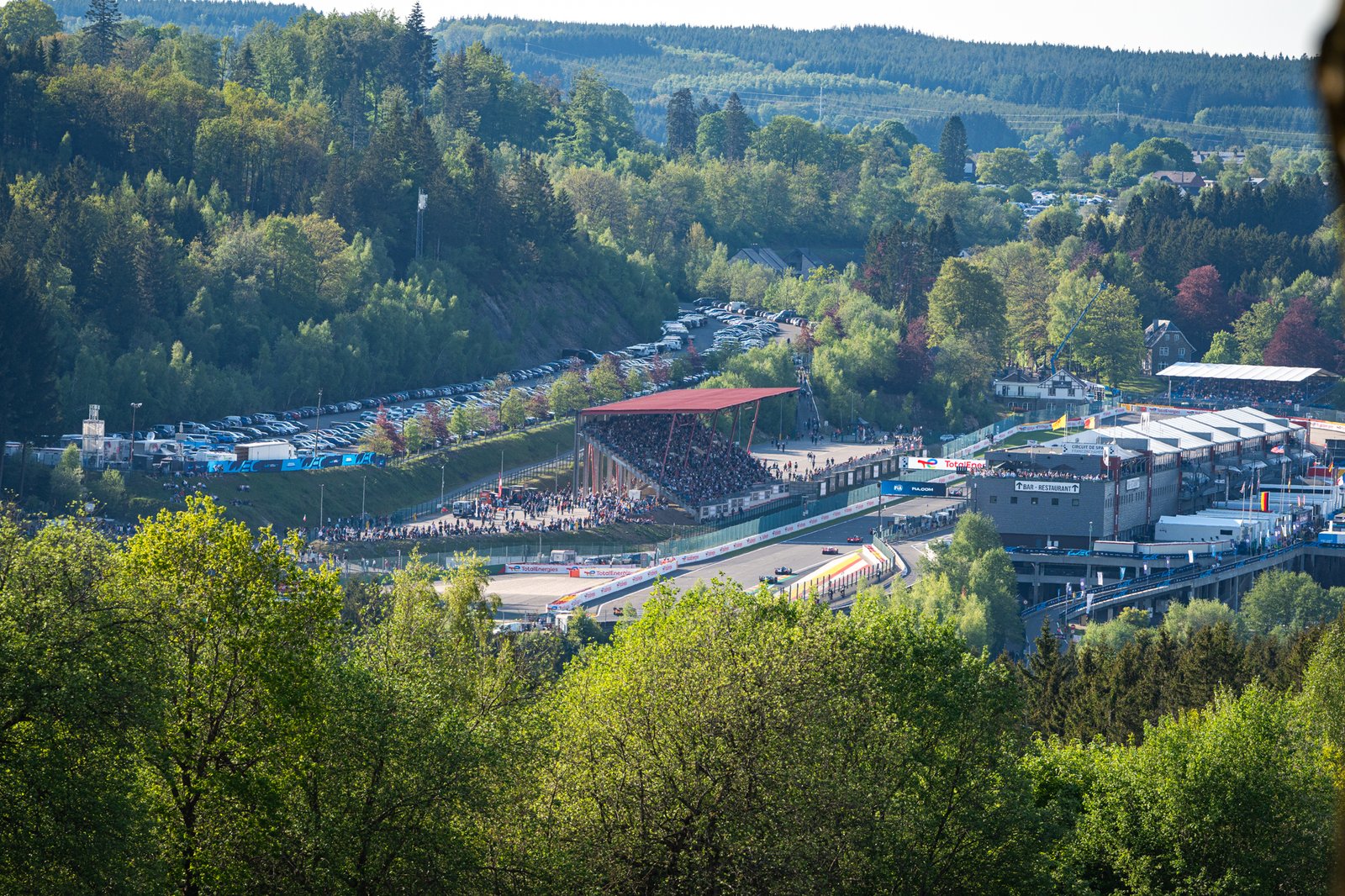 overview shot over the trees, seeing the pit straight grandstand and finish line of Spa Francorchamps